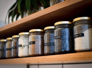 The pantry organising with containers concept in a row of labelled jars on a shelf, containing spices