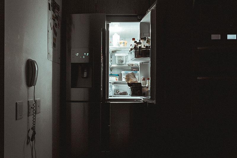 Lit-up fridge interior in a dark room with little mess