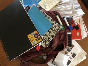 Scattered school bag, visual art diary, markers and stationery, signifying end of year school clutter