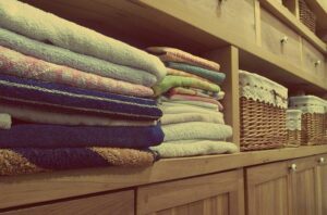 How to stay tidy – do this. Timber shelves contain neatly folded towels and wicker baskets