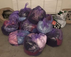 Letting go of stuff, approx. 10 pink plastic bags of clothes are tied up and piled on the carpet