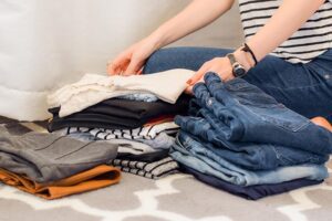 A professional organiser in Melbourne folds jeans and trousers into 3 neat low piles