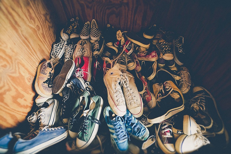 Approximately 25 pairs of sneakers line the bottom of a wardrobe to signify living with teenagers