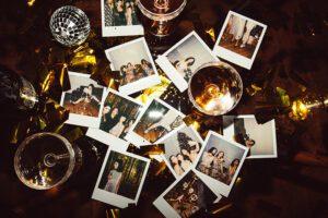 12 polaroid photos are scattered on a table amidst other mess, to show decluttering sentimental items