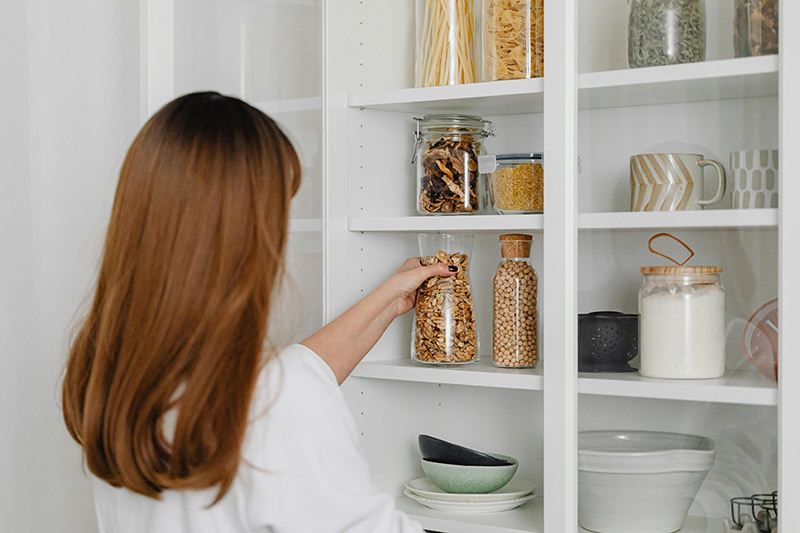 A woman lovingly puts jars of pantry staples onto a shelf